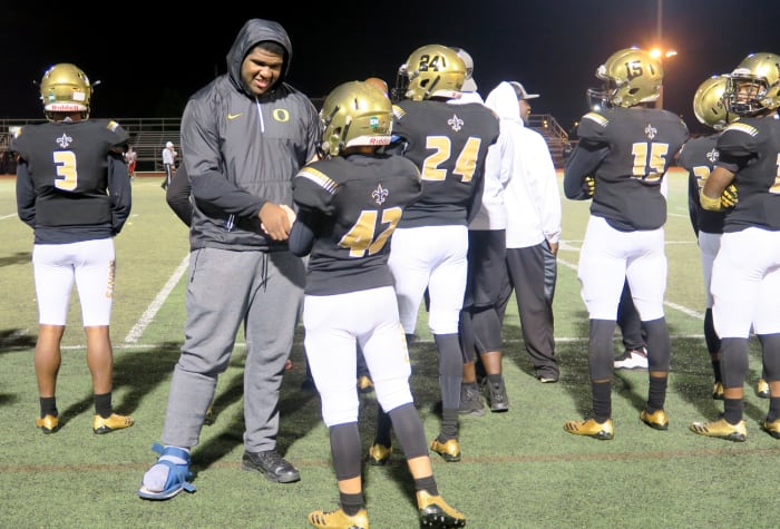 Justin Johnson (in boot), who’s committed to Oregon, gives pointers on the sideline to a teammate.